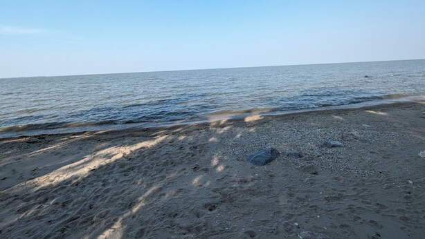 En strand med klart himmel og roligt hav.