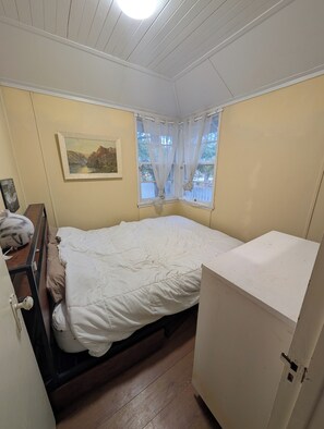 A small, single-bed room with a wooden floor, a white bed, a small desk with a chair, a white wardrobe, and a window with sheer curtains. - Southern Charm, 4-bed cottage in Sandy Hook, fishing, swimming, hiking, relaxing (Sandy Hook)