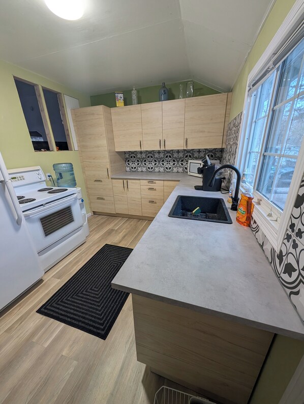 A compact kitchen with a built-in stove, a sink, and wooden cabinets.
