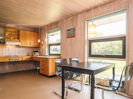 A compact kitchen with wooden cabinets, a stove, and a dining area with a table and chairs.