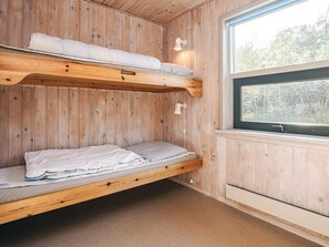 A wooden cabin room with bunk beds, a window, and a wall-mounted light fixture. - 4 Person Holiday Home in Hals (Hals)