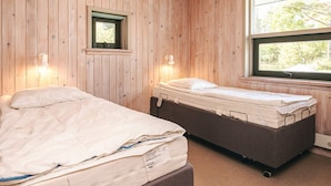 Ein Zimmer mit zwei Betten, Holzwänden, einem Fenster und einem kleinen Spiegel.