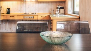 Eine moderne Küche mit Holzschränken, einem Herd und einem Waschbecken. Auf dem Tisch steht eine Glasbowl.