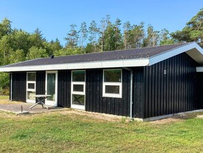 A single-story building with a black exterior, a covered porch, and a small table.