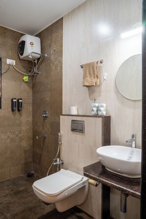 A bathroom with a toilet, sink, towel rack, and a wall-mounted heater. - Goan Hideaway - Uno (Siolim)