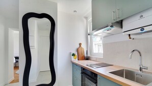 Une cuisine moderne dotée d’un grand miroir noir, d’une planche à découper en bois, d’un évier en acier inoxydable et d’un four encastré.
