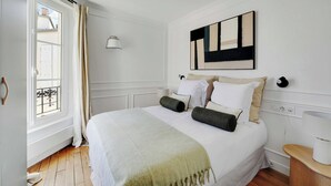 Une chambre à coucher avec un lit, une fenêtre, un tableau et une table de chevet.