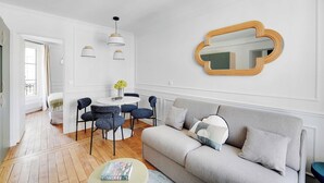 Un salon moderne avec un canapé gris, une table basse ronde et un coin repas comprenant des chaises bleues et une table blanche.