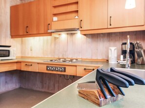 Una cocina con armarios de madera, un microondas, una estufa y un bloque de cuchillos sobre la encimera.