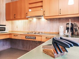 A kitchen with wooden cabinets, a microwave, a stove, and a knife block on the counter.