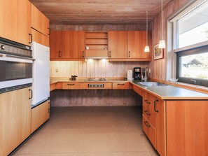 Eine kleine Küche mit Holzausstattung, einem Backofen, einer Kaffeemaschine und einem Fenster mit Blick.