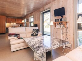 A modern interior with a marble table, a sofa with a blanket, wooden walls, and a television mounted on the wall.