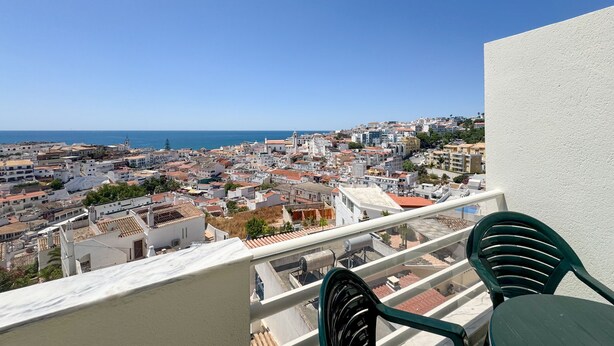 Ein Balkon mit Blick auf eine Küstenstadt, einschließlich Gebäude und Meer.