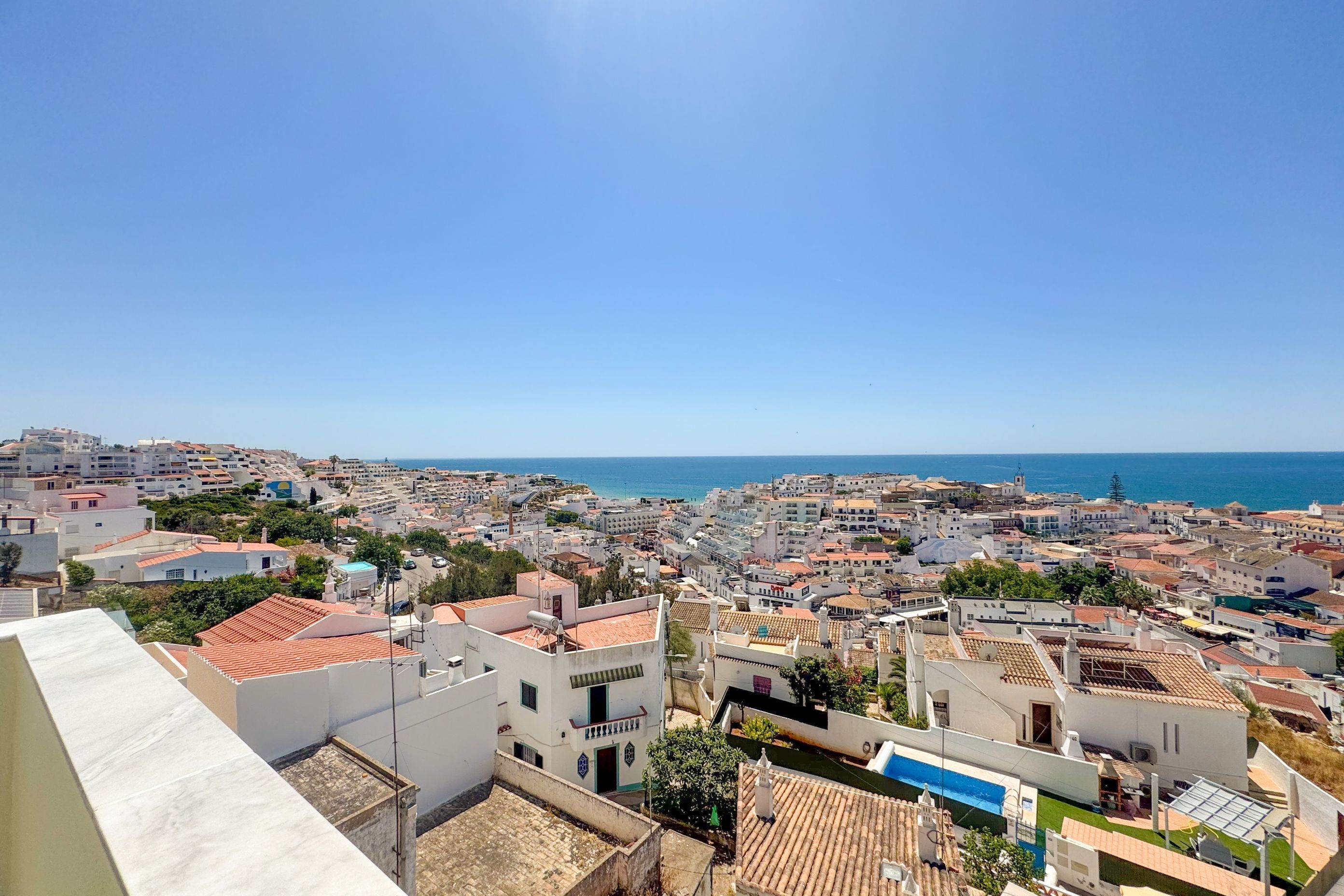 Un paisaje urbano costero con vista al mar, con edificios de arquitectura variada y un cielo despejado.