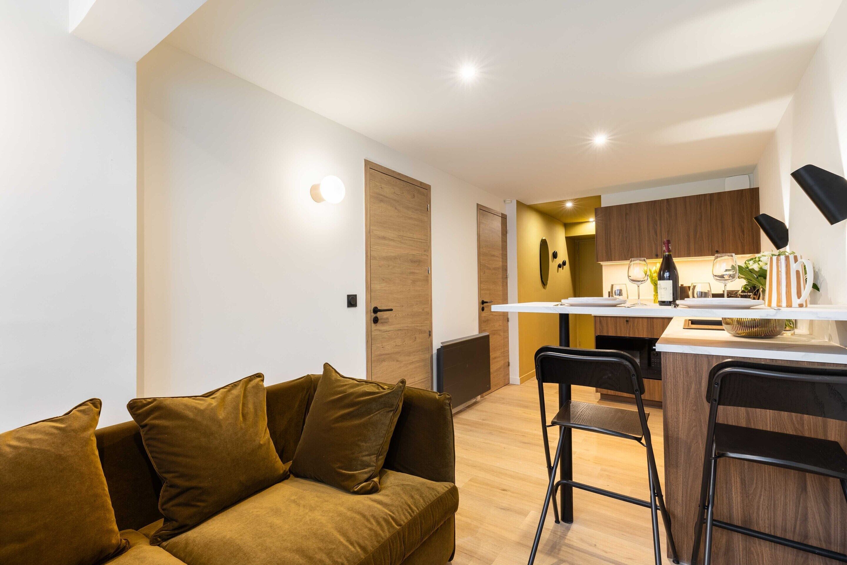 A modern kitchen with a central island, wooden cabinets, and bar stools.