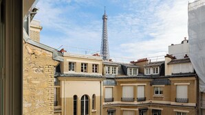 Näkymä Eiffel-tornille rakennuksesta, jossa on useita parvekkeita ja ikkunoita.