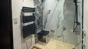 A modern bathroom with a shower, a bench, and a toilet. - Imperial Rabat- Make it Yours (Rabat)