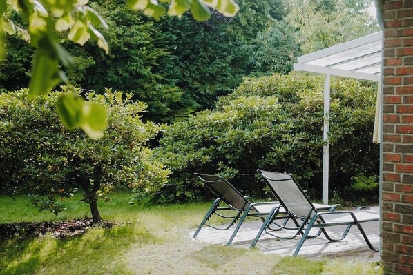 A patio area with two lounge chairs and a pergola structure.