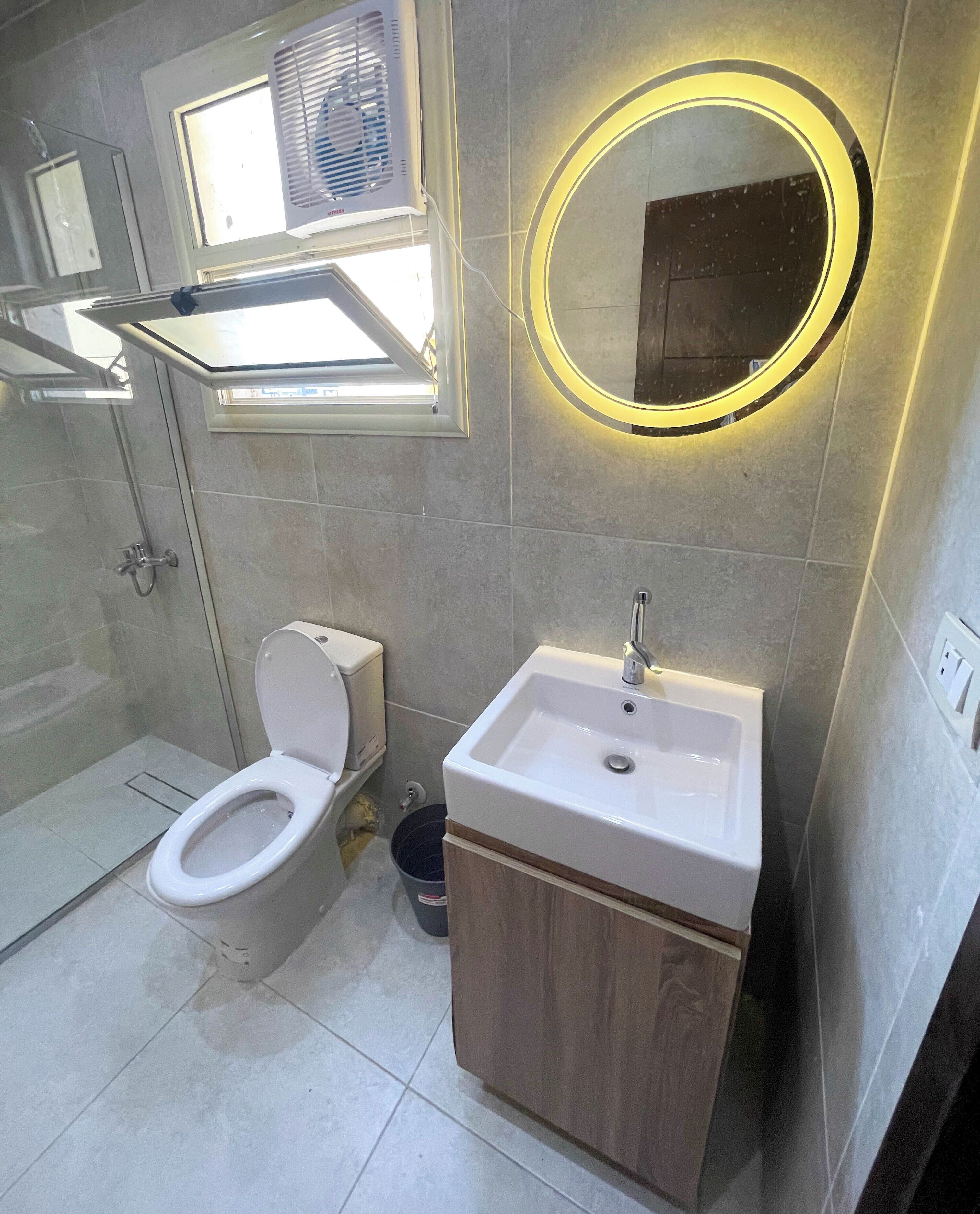 A modern bathroom with a toilet, sink, and shower.