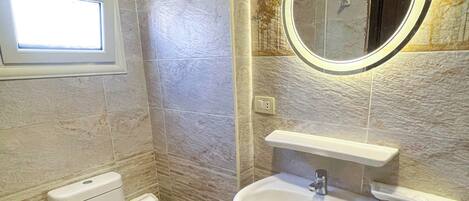 A bathroom with a toilet, sink, and mirror.