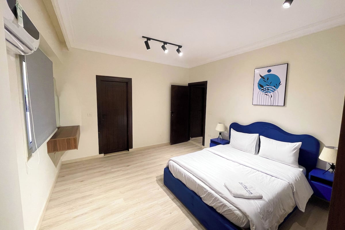 Una camera da letto con un letto, comodini, condizionatore d'aria a parete e una porta.