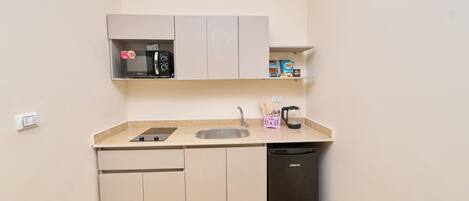 A compact kitchenette with a microwave, a coffee maker, and a dishwasher.