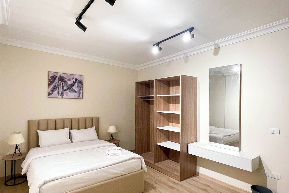 Una camera da letto moderna con un letto, comodini, un armadio e uno specchio.