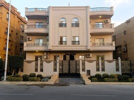 A multi-story building with balconies, air conditioning units, and a gated entrance.
