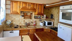 A kitchen with wooden cabinets, a microwave, a refrigerator, and a dishwasher. - Vacation home in Le Pouliguen - Pets welcome! (Le Pouliguen)