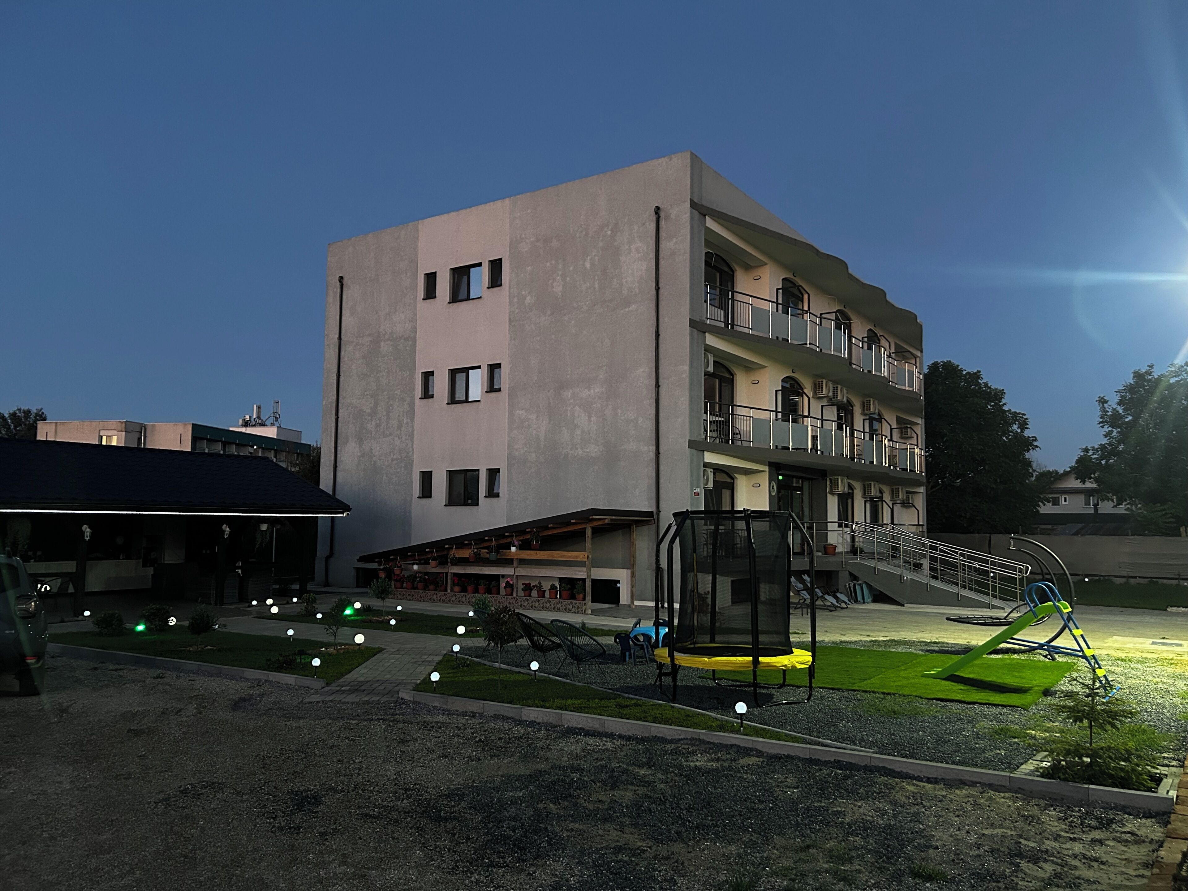 A multi-story building with balconies and a covered outdoor area with seating and a trampoline.