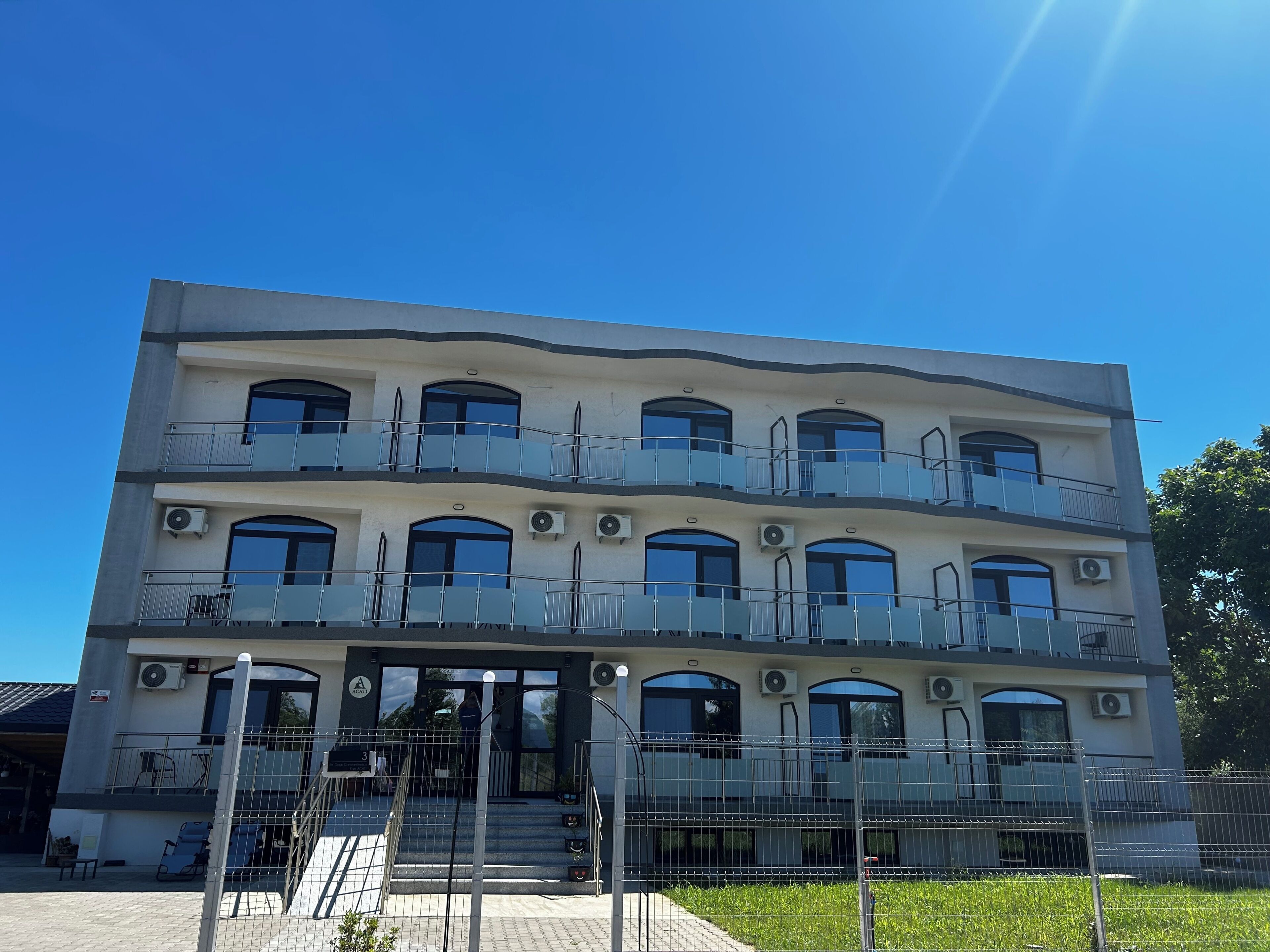 A multi-story building with balconies, air conditioning units, and a gated entrance.