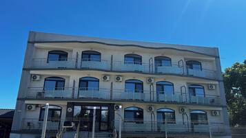 A multi-story building with balconies, air conditioning units, and a gated entrance.