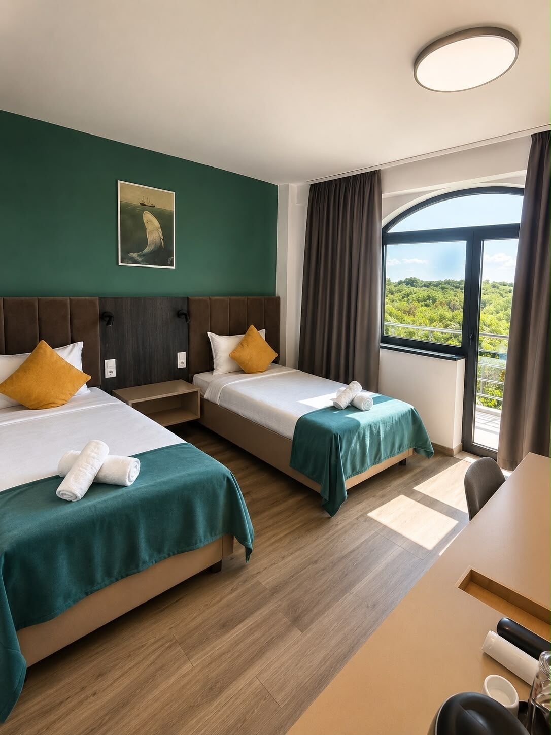 Habitación de hotel con dos camas, un escritorio y un ventanal con vistas.