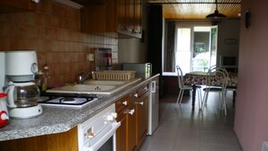 Una cocina con armarios de madera, encimera de granito, cafetera y comedor con mesa y sillas.