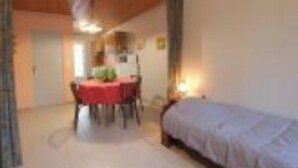 Una habitación con una cama, una mesa de comedor con sillas y una zona de cocina.