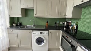 A compact kitchen with a washing machine, a sink, and a stove.