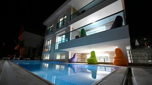 Ein modernes Hotel mit Schwimmbad, mehreren Balkonen und bunten Sitzsäcken.