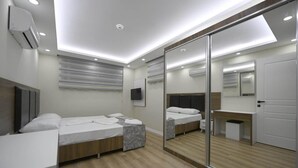 Ein modernes Schlafzimmer mit zwei Betten, einem großen Spiegel und einem eingebauten Kleiderschrank.