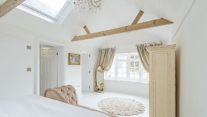 Een slaapkamer met een groot bed, een houten garderobe, een spiegel en een raam met gordijnen.