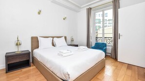 Ein Hotelzimmer mit einem großen Bett, einem Nachttisch, einer Lampe und Blick auf den Balkon.