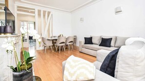 Ein modernes Wohnzimmer mit einer Couch, einem Esstisch mit Stühlen und einer Zimmerpflanze.