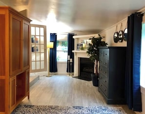 Une pièce avec un meuble en bois, une cheminée, une plante et un rideau bleu.