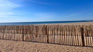 A beach with a wooden fence in the foreground and a clear blue sky. - Apartment in Valras Plage With View (Sérignan)