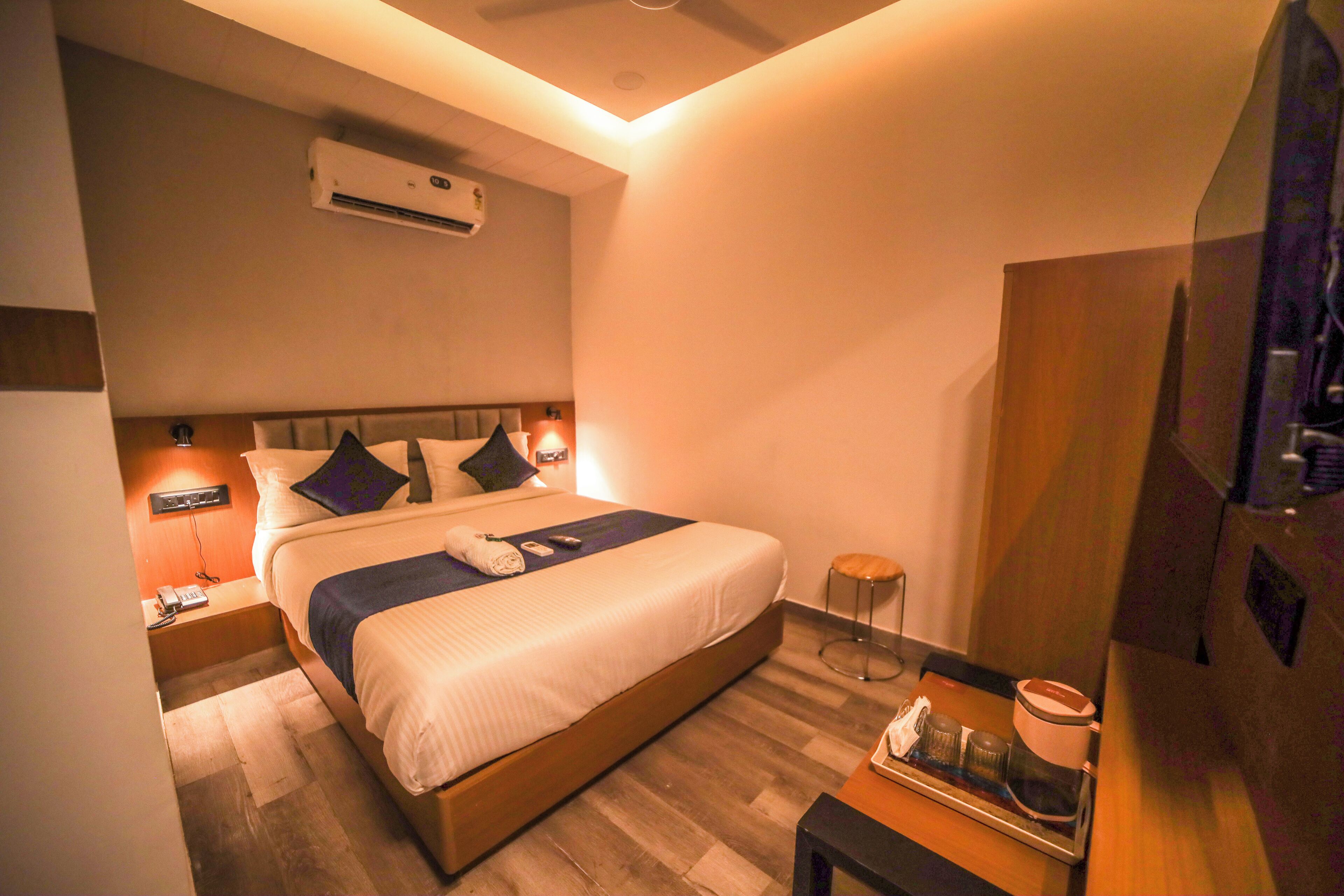 Una habitación de hotel moderna con una cama grande, lámparas de noche, una mesita con una bandeja y un equipo de aire acondicionado en la pared.