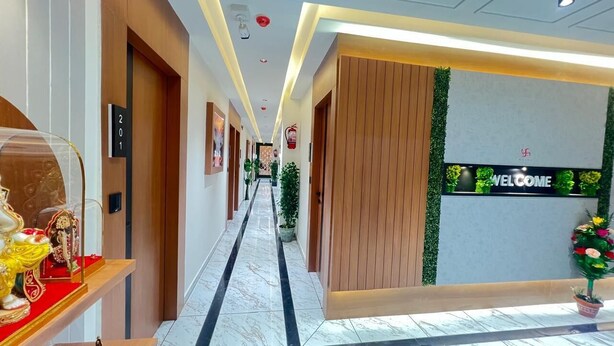 A hotel corridor with a welcome sign, wooden paneling, and a marble floor. - HOTEL NEST ICON  (Ahmedabad)