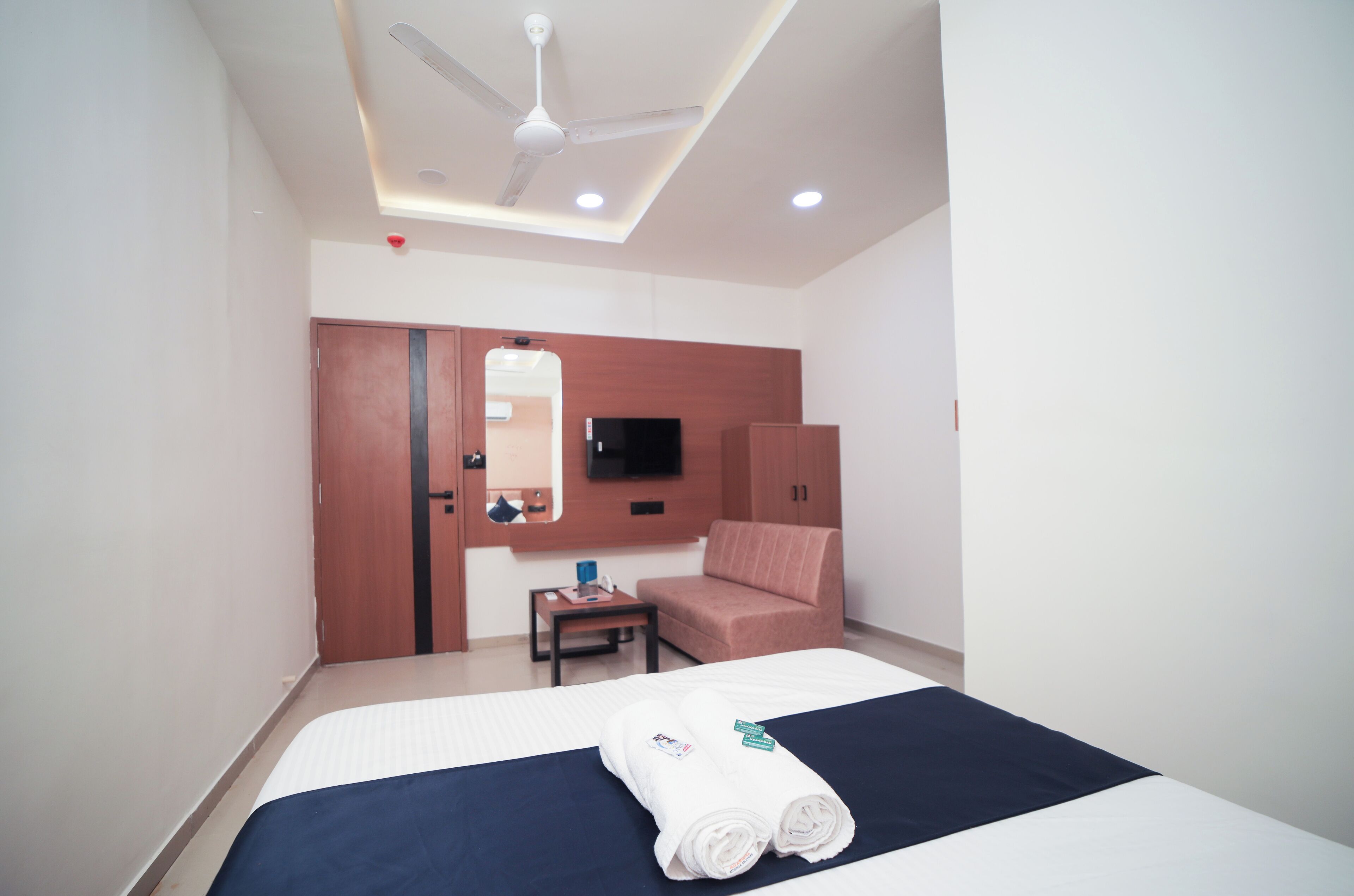 A hotel room with a bed, a desk, a chair, a TV, and a wardrobe.