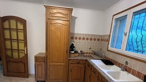 A kitchen with wooden cabinets, a sink, and a window with a view of greenery. - Comfort villa on the lake (VINS SUR CARAMY (83170))