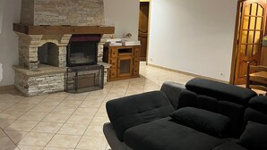 A living room with a stone fireplace, a wooden cabinet, a black sofa, and a small round table. - Comfort villa on the lake (VINS SUR CARAMY (83170))