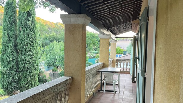 A covered balcony with tiled flooring, a white chair, and a table. - Comfort villa on the lake (VINS SUR CARAMY (83170))