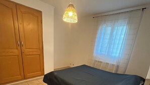 A bedroom with a bed, a nightstand, a lamp, a window with curtains, and a wardrobe. - Comfort villa on the lake (VINS SUR CARAMY (83170))